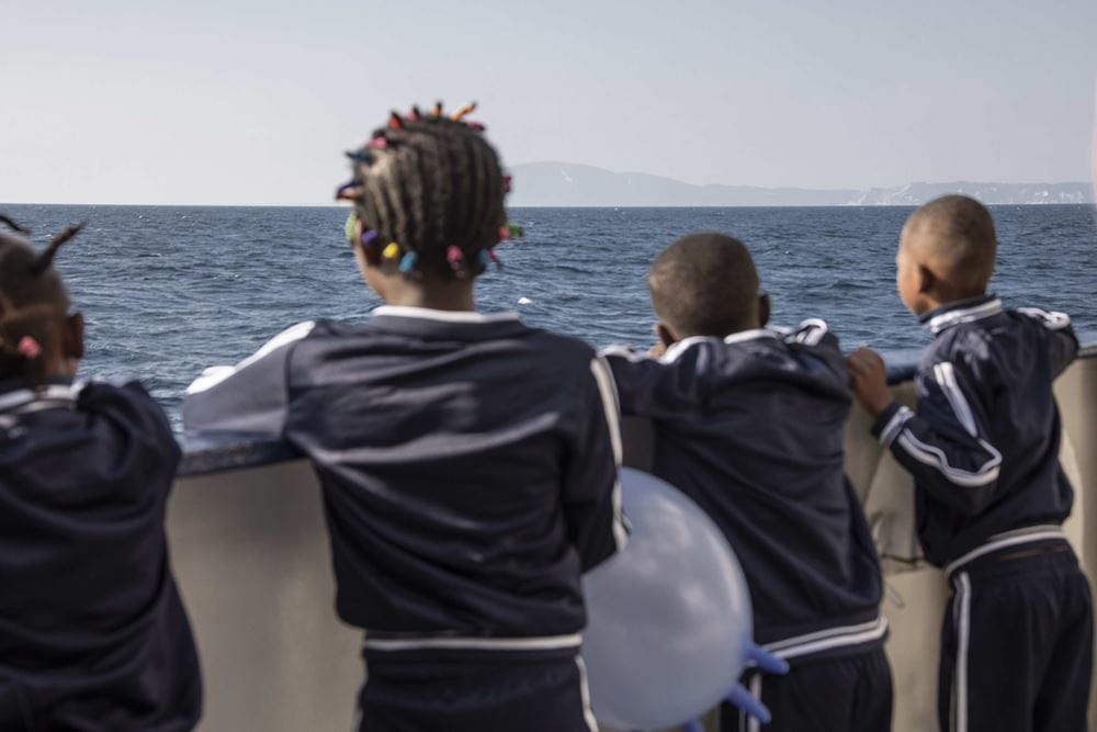 Kinder stehen an der Reling eines Schiffes und sehen am Horizont Land (Quelle: Danilo Campailla)